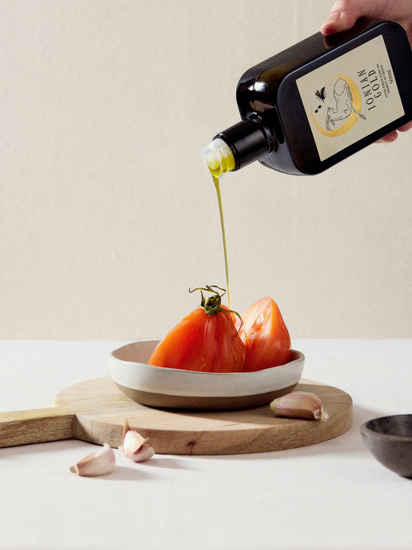 Ionian Gold olive oil being poured onto tomatoes on a wooden board