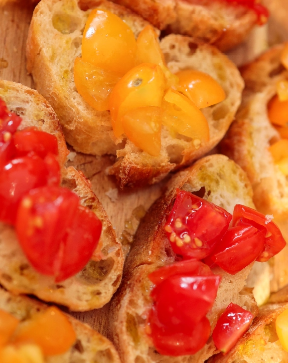 Crostini topped with red and yellow tomatoes, drizzled with Ionian Gold olive oil