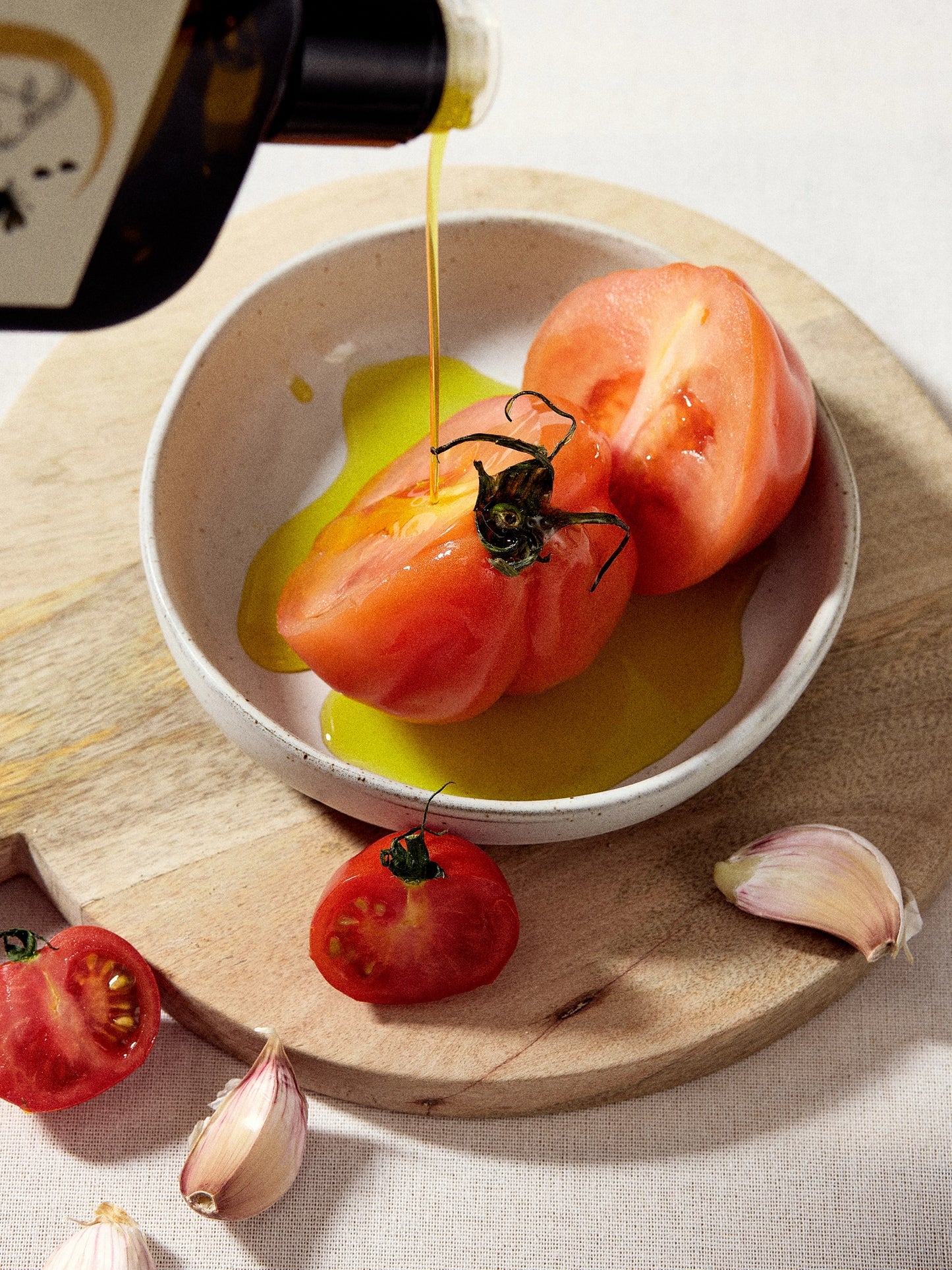 Pouring Ionian Gold olive oil onto tomatoes